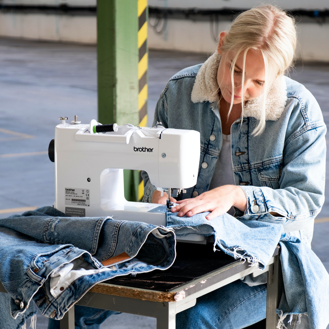 Kvinde der sidder og syer igennem denim på Brother HF37 symaskinen, som kan sy igennem hårde materialer og flere lag. 